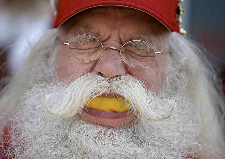 Bill Neely winces as he bites into a lemon to raise awareness for leukemia at Santa Day in Medina. Around 65 Santas came out to Medina Square and took part in the lemon challenge.  (Leah Klafczynski / Akron Beacon Journal)
